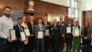Seven new Associate Fellows presenting their certificates, posing in a row with Chair Peter McCrea, Vice Chancellor Ashley Wheaton and Deputy Vice Chancellor Jane Fawkes
