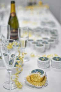A half eaten centenary cupcake alongside other cupcakes, champagne flutes and a champagne bottle