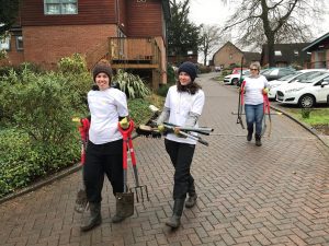 Staff members holding gardening equipment in the Purley Park car park