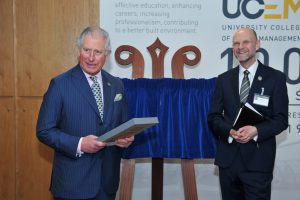 UCEM's Patron, His Royal Highness, The Prince of Wales in the Horizons building holding his gifted UCEM centenary tie