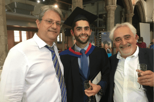 A recent graduate having his picture taken with his Father and UCEM Tutor, Marios Konstantinidis
