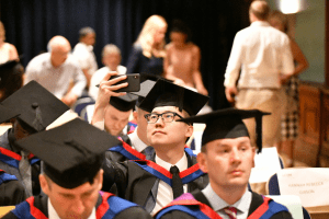 Students at their graduation ceremony in Reading Town Hall. One of them taking a selfie