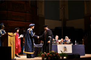 UCEM Principal, Ashley Wheaton, shaking the hand of a UCEM student in the graduation ceremony hall
