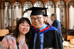 A recent graduate having a photo taken alongside a member of his family