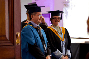 UCEM Head of Subject - Real Estate and Management, Peter Escreet, and Tutor, Hazel Lobo, heading into the Concert Hall for the December 2019 UCEM Graduation ceremony