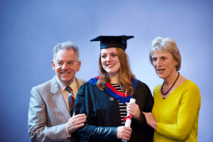 A graduate poses for her official photograph with two family members at the December 2019 UCEM Graduation