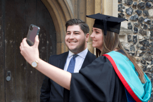 A graduate taking a selfie with her friend at the December 2019 UCEM Graduation