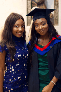 A graduate smiles for the camera with a friend in tow at the December 2019 Graduation