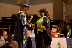 A graduate receiving her certificate on stage at the December 2019 UCEM Graduation