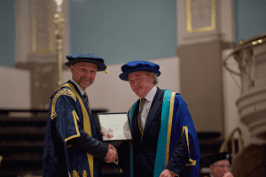 Ben Bolgar being presented a certificate acknowledging him as a UCEM Honorary Fellow at the December 2019 UCEM Graduation