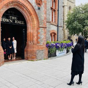 A woman taking a photo of a graduand and family/friends