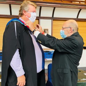 A graduand being fitted for his robe