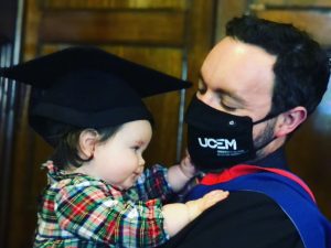 Graduate plays with his baby daughter